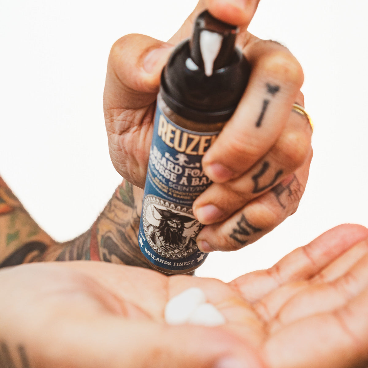 Reuzel Deutschland beard foam in a container, designed for grooming and softening men's facial hair.