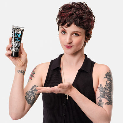 Reuzel Deutschland TAT Buff Exfoliating Wash for tattoo aftercare, with a clear bottle and label showing exfoliating ingredients.