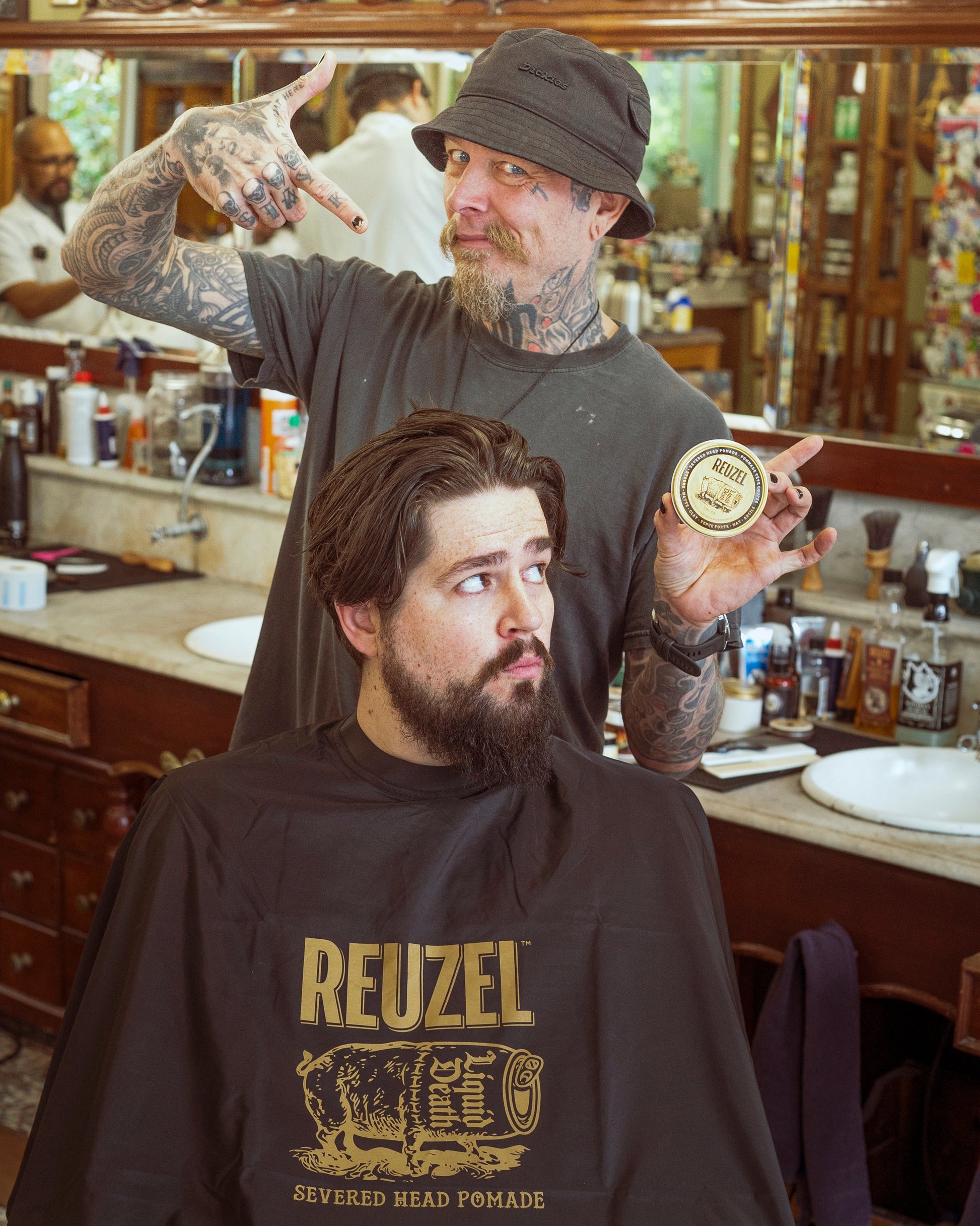 Severed head Reuzel UK barber cape with graphic design, used as stylish merch for barber and grooming enthusiasts.