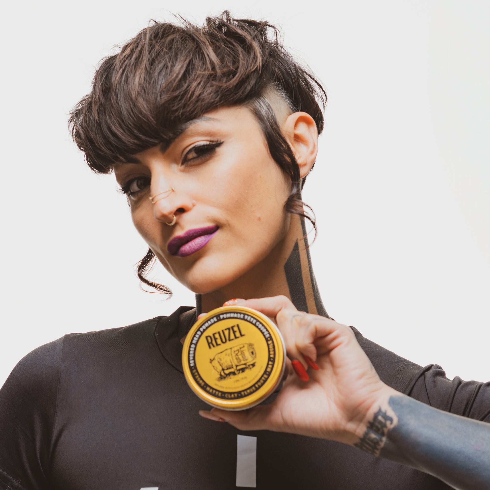 Reuzel Deutschland Severed Head Pomade bottle with Liquid Death branding, featuring a graphic severed head illustration on the label.