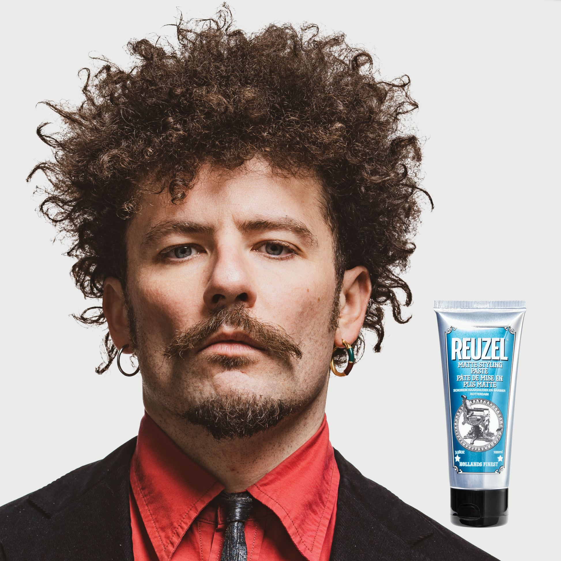 Reuzel Deutschland grooming cream for hair styling, showing the product container with a black lid and label on a plain background.
