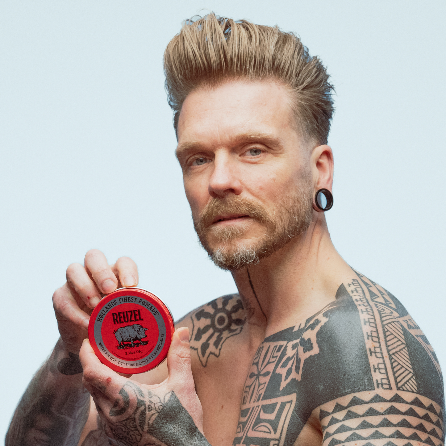 Reuzel Red Pomade in a jar, showcasing the classic red label, used for styling hair with a shiny, firm hold.
