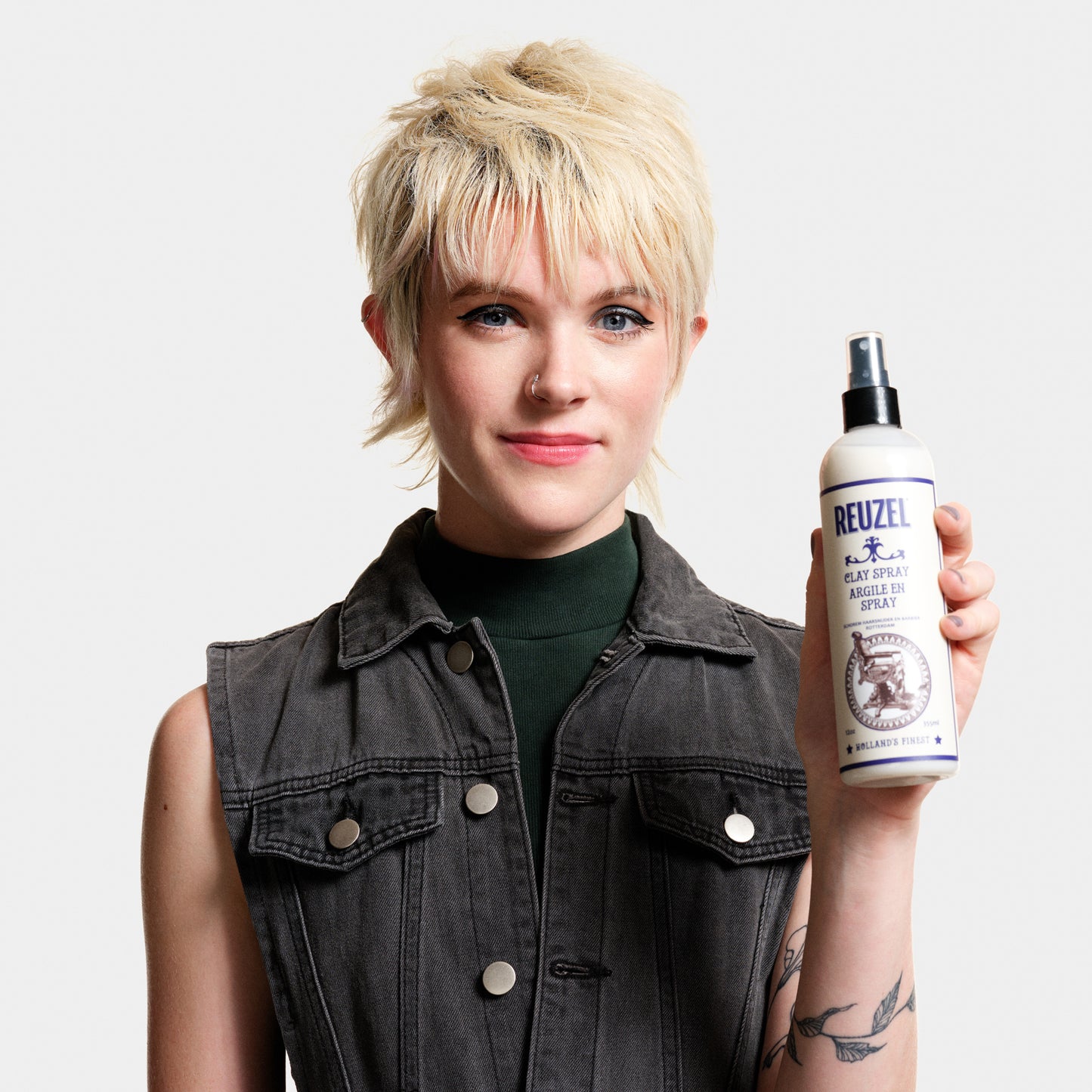 Reuzel Clay Spray for hair styling, featuring a spray bottle with the product label visible, ideal for textured, matte finishes.