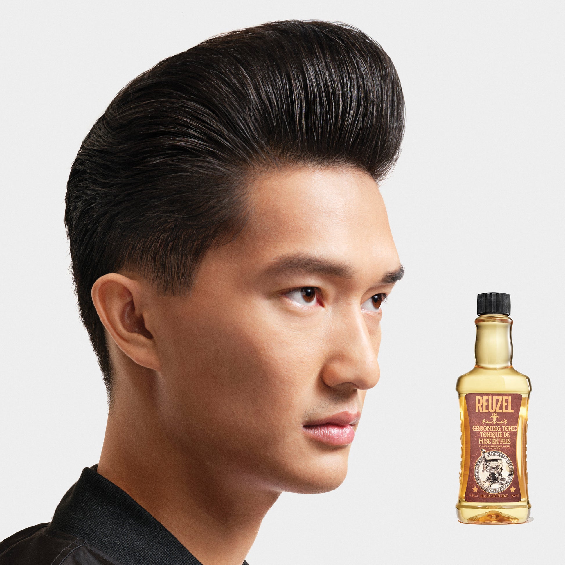 Reuzel Deutschland grooming tonic bottle for hair, featuring a sleek design and label with branding and product details.