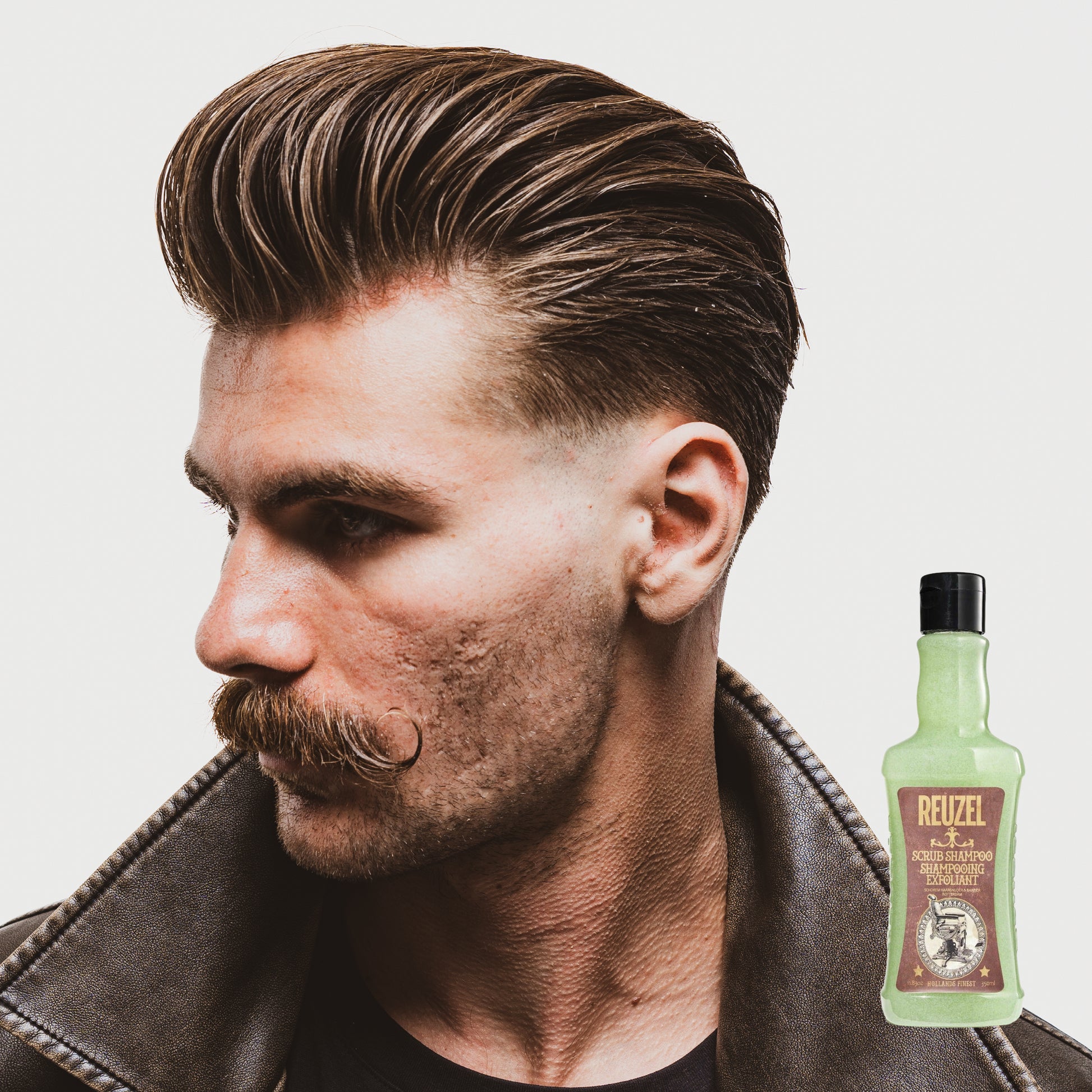 Reuzel Deutschland Scrub Shampoo bottle with pump dispenser, showing the product label and black packaging on a white background.