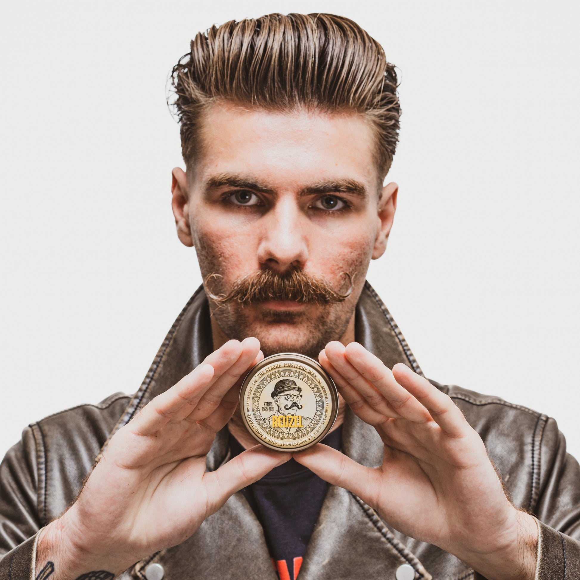 Reuzel Deutschland The Stache Mustache Wax jar with black lid and label, used for shaping and styling mustaches.